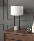 65.5 Inch Tall Floor Lamp With White Drum Shade In Blackened Bronze And Concrete Finish next to candles and decor