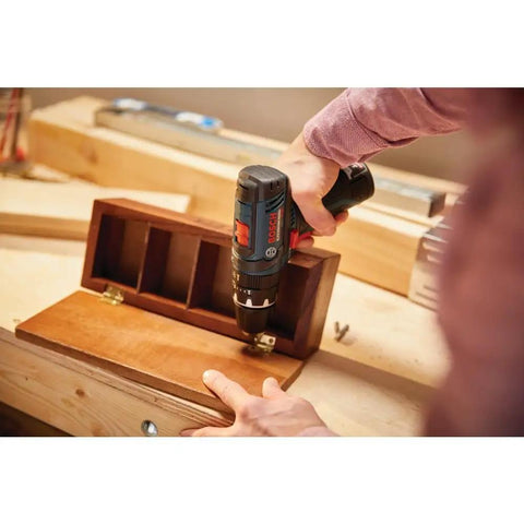 Person using Ultra Compact 12V Max Hammer Drill And Driver Kit with 3/8 Inch Auto Chuck on wooden box, ideal for tight spaces.