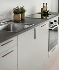 Modern kitchen with antique brass knurled cabinet pulls on white cabinets, highlighting the 5-inch length and vintage industrial style.