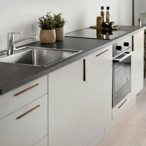 Modern kitchen with antique brass knurled cabinet pulls on white cabinets, highlighting the 5-inch length and vintage industrial style.