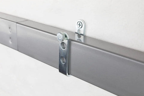 Close-up of a 44-inch door barricade bar with folding brackets installed with hardened screws on a wall.