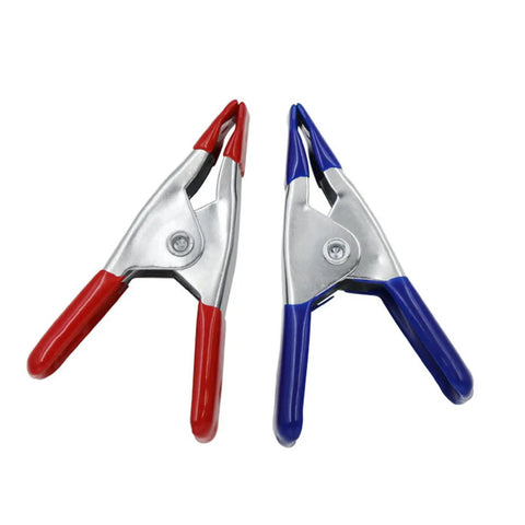 Two 2-inch heavy duty metal spring clamps, one red and one blue, with nonslip grips for photography and woodworking.