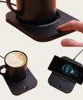 Solidly Built Wireless Charging Mug Warmer And Desk Phone Base With Auto Shut Off Keeps Your Morning Brew Piping Hot While You Charge On The Fly In Classic Black with coffee and smartphone.