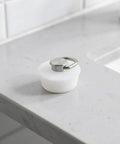 White Silicone Drain Stopper with Ring for Bathtubs and Sinks on a marble countertop, showcasing its elegant design and practicality.