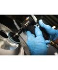 User operating the Badass Quarter Inch Pneumatic Angled Die Grinder Spins 20000 RPM on a metal surface with blue gloves.
