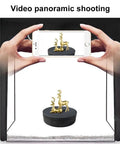 Person photographing a golden deer sculpture on the Emvanv Electric Rotating Display Turntable 360 Auto Spin Platform.