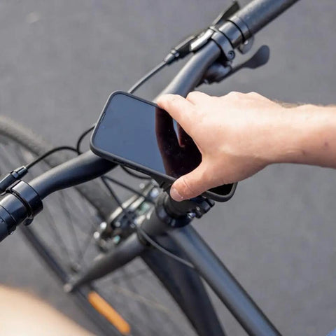 Person using Bike Handlebar And Stem Phone Mount Kit With MAG Universal Adapter And Dual Lock for quick secure phone access.
