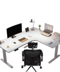 Electric Height Adjustable L-Shaped Standing Desk For Corner Home Office with ergonomic chair and accessories on desk.