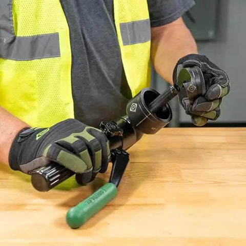 Heavy Duty Hydraulic Knockout Kit With Quick Draw Driver For 0.5 To 2 Inch Holes in use by an electrician on a workbench.