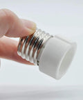 Hand holding E26 E27 To GU10 Ceramic Socket Adapter Built Tough For Heavy Duty Halogen And Led Spotlight Work.