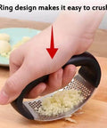 Hand using Stainless Steel Garlic Press Rocker Mincer With Peeler on cutting board to crush garlic effortlessly