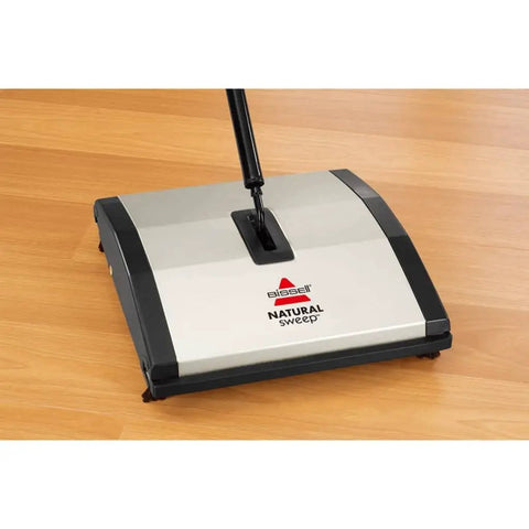 Lightweight Manual Carpet And Hard Floor Sweeper Featuring Dual Rotating Brush Roll Plus Corner Edge Brushes on wooden floor.
