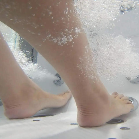 Foot submerged in bubbles from Sleek 32X52 Acrylic Transfer Walk In Tub With Heavy Duty Hydro Massage and Microbubble Jets.