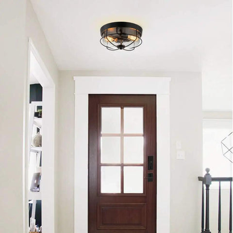 Industrial Black 13 Inch Flush Mount Ceiling Light With Seeded Glass Shade And Metal Cage in entryway.