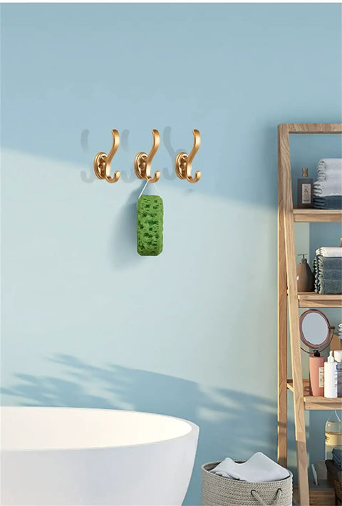 Rock Solid Heavy Duty Wall Mounted Coat Hook For Doors And Walls with three gold hooks holding a green sponge.