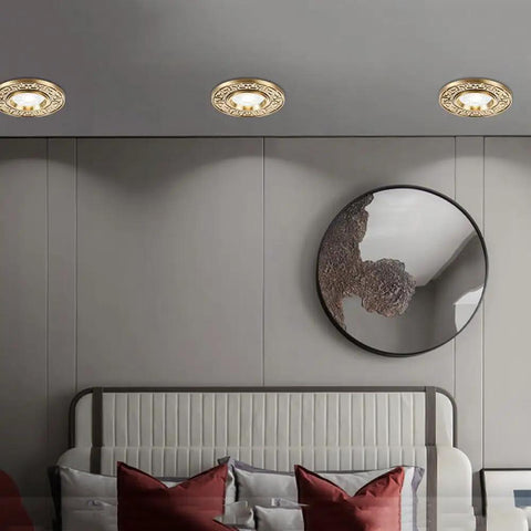 Three brass XYIANG 9-Pack Recessed Lighting Housing Trim Kits above a bed in a stylish modern bedroom setup.