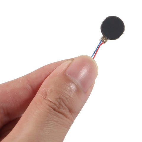 Hand holding one mini flat coin type vibration motor 10x3mm, 12000RPM DC 3V self adhesive for DIY haptic feedback in electronics
