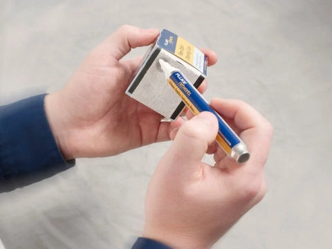 Fluke Networks NFC-SOLVENTPEN fiber optic cleaning solvent pen blue body with yellow label and white tip held.