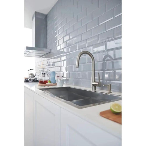 Modern kitchen with stainless steel faucet and tiled backsplash, featuring sleek design and contemporary style in a bright setting.
