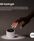 Hand reaching for a jar of nail enhancement product on a dark background