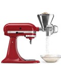 KitchenAid KGM all-metal grain mill attachment mounted on a red stand mixer; metal hopper with grain