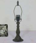 Zinc alloy base of stained glass table lamp with vintage frame beside it, no bulb shown