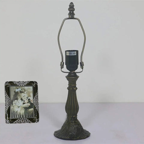 Zinc alloy base of stained glass table lamp with vintage frame beside it, no bulb shown