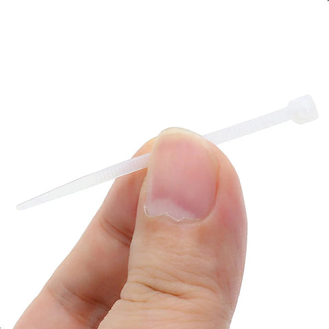 Close-up of hand holding a white nylon zip tie from 100 Pcs Self Locking Nylon Cable Ties 60mm Long, 2.5mm Wide, 18 Lbs Tensile Strength set.