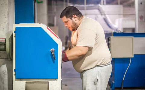 Person using a blue industrial sandblasting machine, possibly utilizing Pro Grade Glass Bead Sandblasting Media For Rust Paint And Dirt Removal 20 To 30 Mesh Medium Large Size 1 Pound Bag Delivers Gentle Surface Cleaning And Smooth Prep For Painting Bonding.