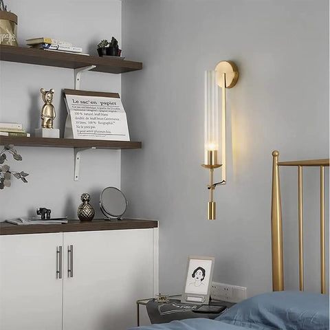 Modern Long Tube Wall Sconce In Brushed Gold Metal And Frosted Glass casting a chic warm glow in a stylish bedroom.