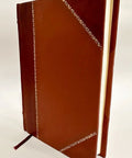 Book: Lathe Work for Beginners, brown leather-bound cover with white decorative stitching and a ribbon bookmark.