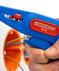 Close-up of a hand using the Automatic Wire Stripper No 5 with Side Cutter for 0.2 to 6 mm2 cables on a wire, orange background.