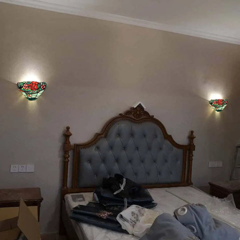 Rose Flower Tiffany Style Stained Glass Wall Sconce Lamp 12 Inch Wide Handmade Home Decor in bedroom setting with warm glow