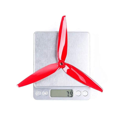 Red propeller from 8 Pack 3 Blade High Speed Drone Propellers For Racing FPV Drones on digital scale weighing 7.9 grams