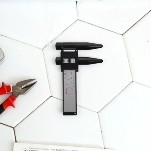 OHPHCALL 2pcs Wheel Hub Diameter Ruler ABS Measuring Tool for Automotive on a tiled surface with pliers.