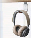 Headphones hanging on under desk headphone stand mount with self adhesive tape L shape headset holder bracket for easy no drill setup and clean cable management black finish.