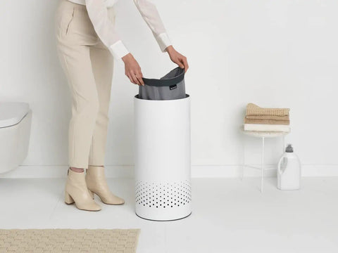 Person placing bag into 9 Gal White Laundry Hamper With Quick Drop Lid For Easy Toss In Ventilation Holes Corrosion Resistant Materials Hygienic And Discreet Laundry Basket For Bathroom Or Laundry Room