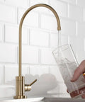 Hella Durable Standalone Kitchen Water Filter Faucet In 100 Percent Lead Free Brass With A Slick Spot Free Antique Champagne Bronze Finish For Fresh Filtered Drinking Water pouring water into a glass.