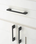Matte black cabinet pulls installed on white cupboard drawers, featuring 10 Pack Matte Black Cabinet Pulls 5 Inch 128mm Hole Centers Kitchen Cabinet Handles For Cabinets Cupboard Drawers Hardware ZH0060 Durable, Easy To Install Long Lasting Finish.