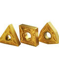 Three gold carbide lathe turning inserts (two triangular, one square) with center holes.