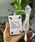 Hand holding an ACR122u A9 Dope Reader Writer For Rewritable UID Changeable Cards with cable against a leafy background.