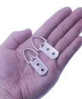 Heavy Duty D Ring Picture Hangers With Included Wall Screws, 20 Pack, large silver hardware held in hand for art mounting.