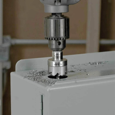 Front view of Klein Tools 31872 heavy-duty hole saw attached to a drill, cutting into a metal surface with metal shavings.