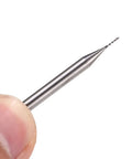 Close-up of a 0.6mm carbide end mill with a 1/8 inch shank for PCB engraving, held by fingers