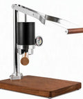 Badass Stainless Steel Manual Lever Espresso Maker With Integrated Pressure Gauge on wooden base, side view.