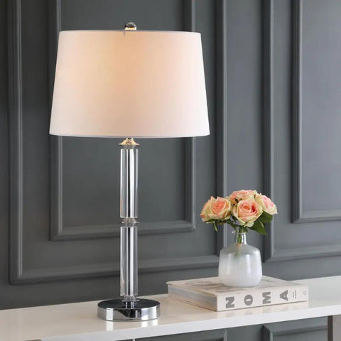Vendome Modern Clear Glass 29 Inch Table Lamp with White Polyester Shade and Crystal Base on a Desk Next to Flowers and Books