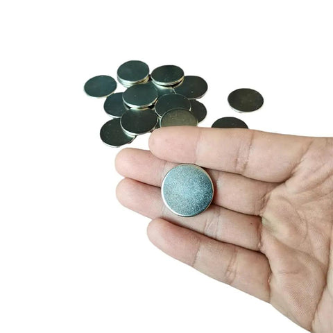 Slick Nickel Coated Steel Discs.98 Inch Diameter with smooth chamfered edges held in hand, surrounded by more discs.
