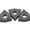 Three triangular WNMG432 carbide turning inserts with central bore for lathe tool holder; bronze finish.