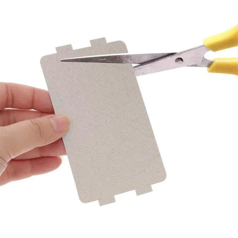 Microwave Waveguide Cover Made From Mica Sheet Heat Resistant Thermal Insulation Pad being cut with scissors, 4.57 by 2.56 inches.