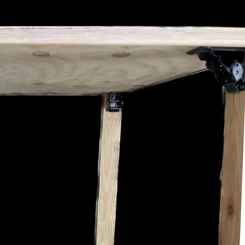 Badass Heavy Duty Folding Brackets For Tables And Bed Legs, 8 Pack Self Locking Hinges With Wood Screws, Sturdy Cold Rolled Steel Extension Supports For Workbenches, Black mounted on a wooden table leg.